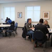 Volunteers and students all sitting at tables together at the 30 Minute Mentors Event